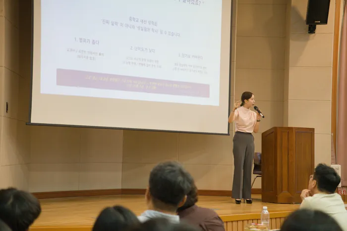강단에서 마이크를 들고 발표하는 모습과 앉아 듣는 참석자들