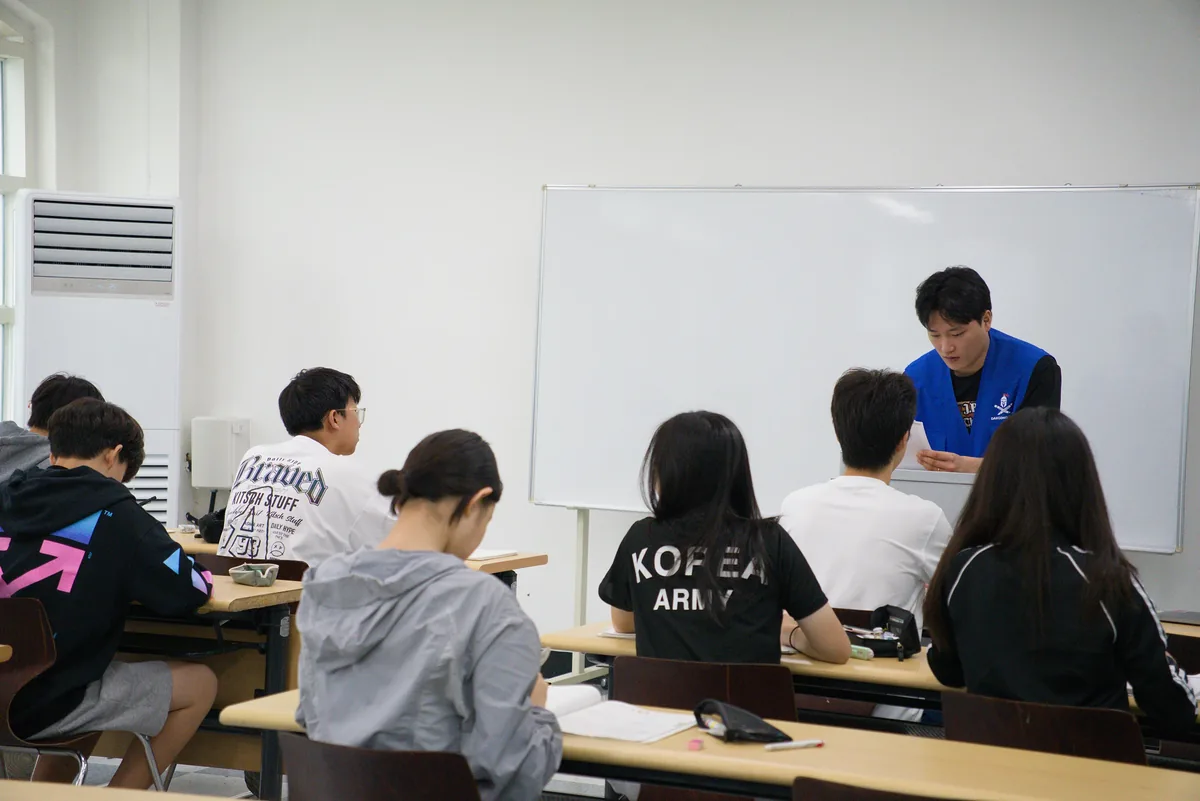 강의실에 앉은 학생들이 앞에 선 강사의 수업을 듣는 모습