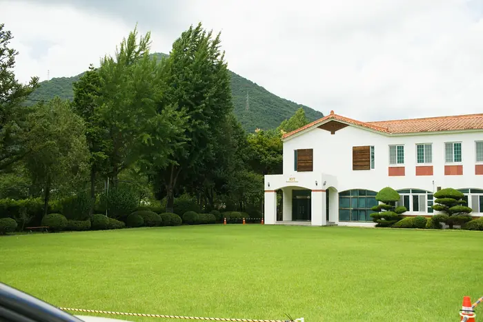 산을 배경으로 잔디 마당 건너편에 선 캠프 건물