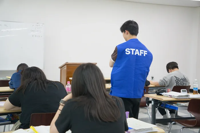 STAFF 조끼를 입은 담당자가 자습실 안을 돌며 학생들의 진행 상황을 살피는 모습